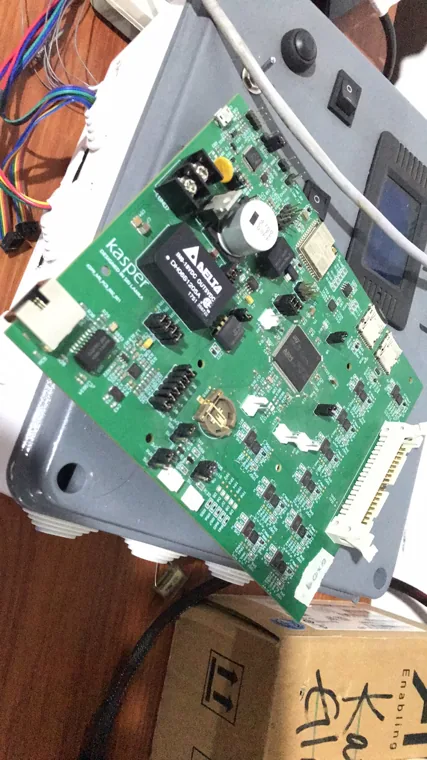 Populated green PCB mounted in an open gray enclosure.
