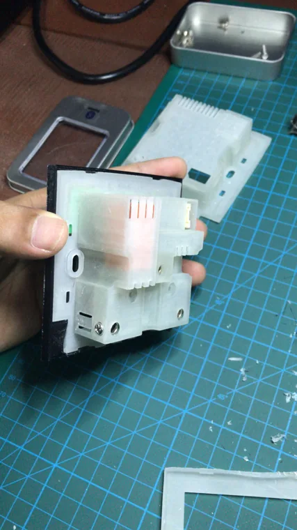 Hand holding a translucent printed assembly above a cutting mat.