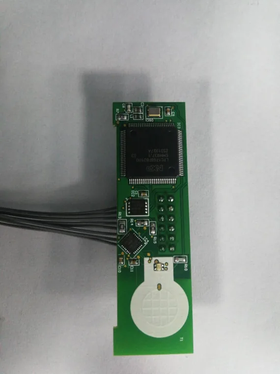 Long narrow green PCB with a wired connector and circular white area.